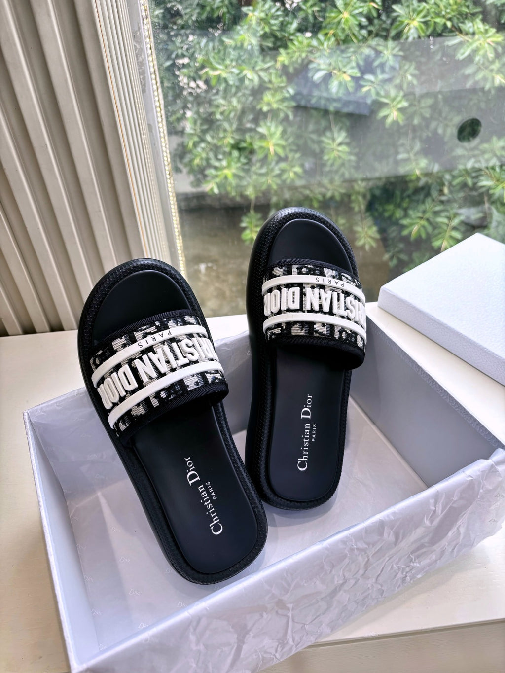 Pair of black Dior slide sandals with white printed strap and cushioned sole