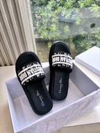 Pair of black Dior slide sandals with white printed strap and cushioned sole