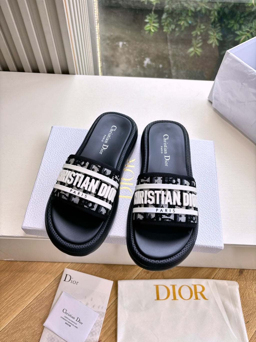 Black Dior slide sandals with white printed strap, tops and footbeds shown