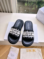 Black Dior slide sandals with white printed strap, tops and footbeds shown