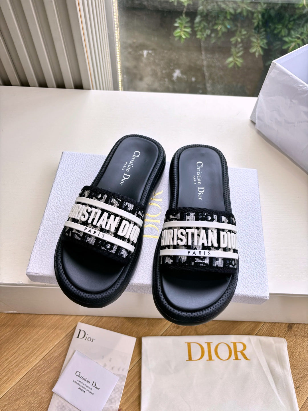 Black Dior slide sandals with white printed strap, tops and footbeds shown