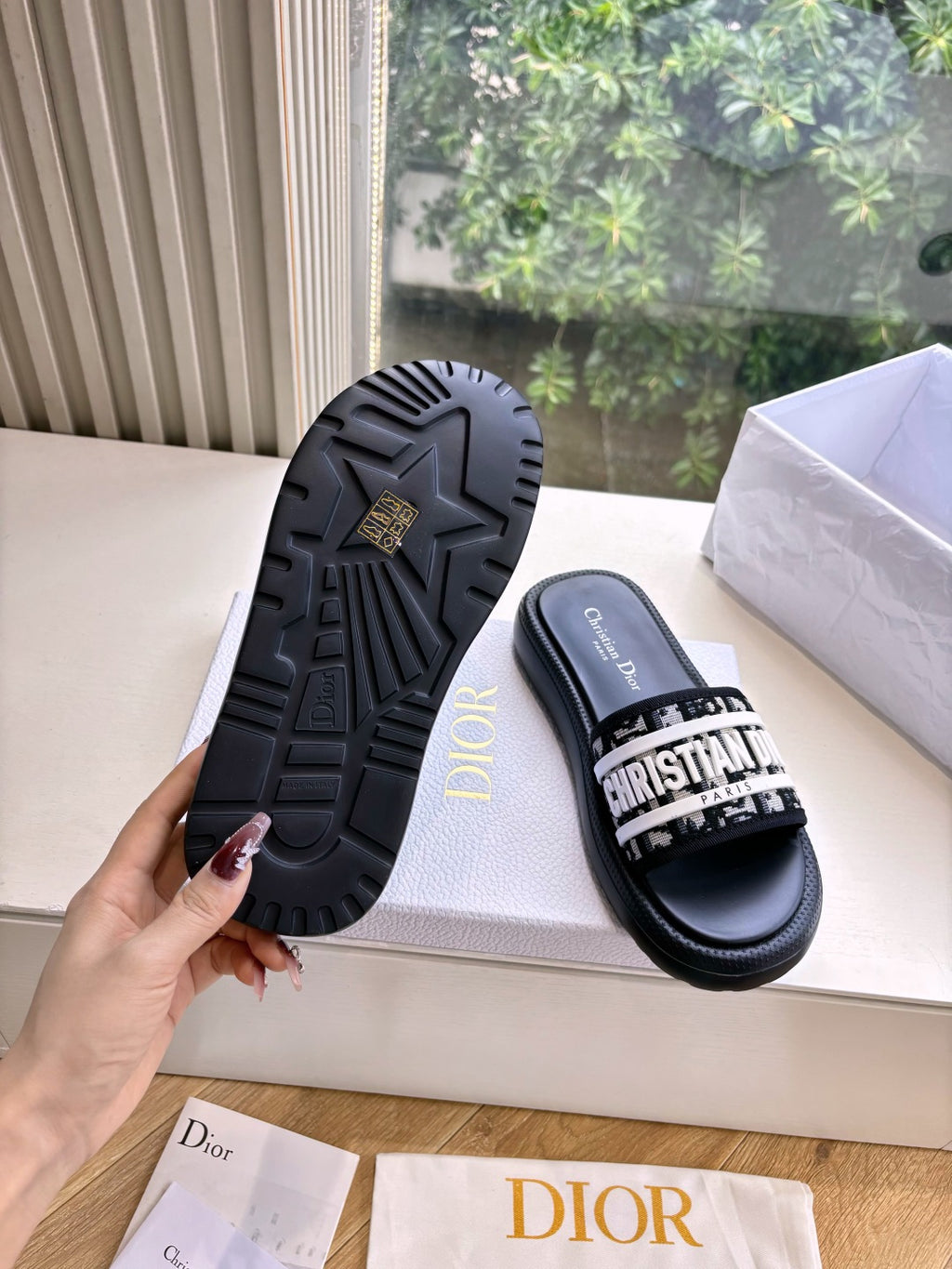 Black Dior slide sandals with textured tread sole and white logo strap