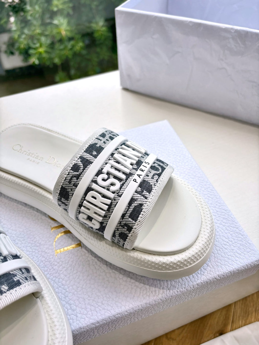 White Dior slide sandal, close-up of black logo band strap