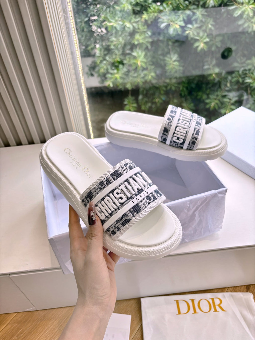 White Dior slide sandals on raised platform, logo band across front strap