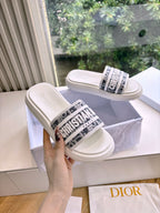 White Dior slide sandals on raised platform, logo band across front strap