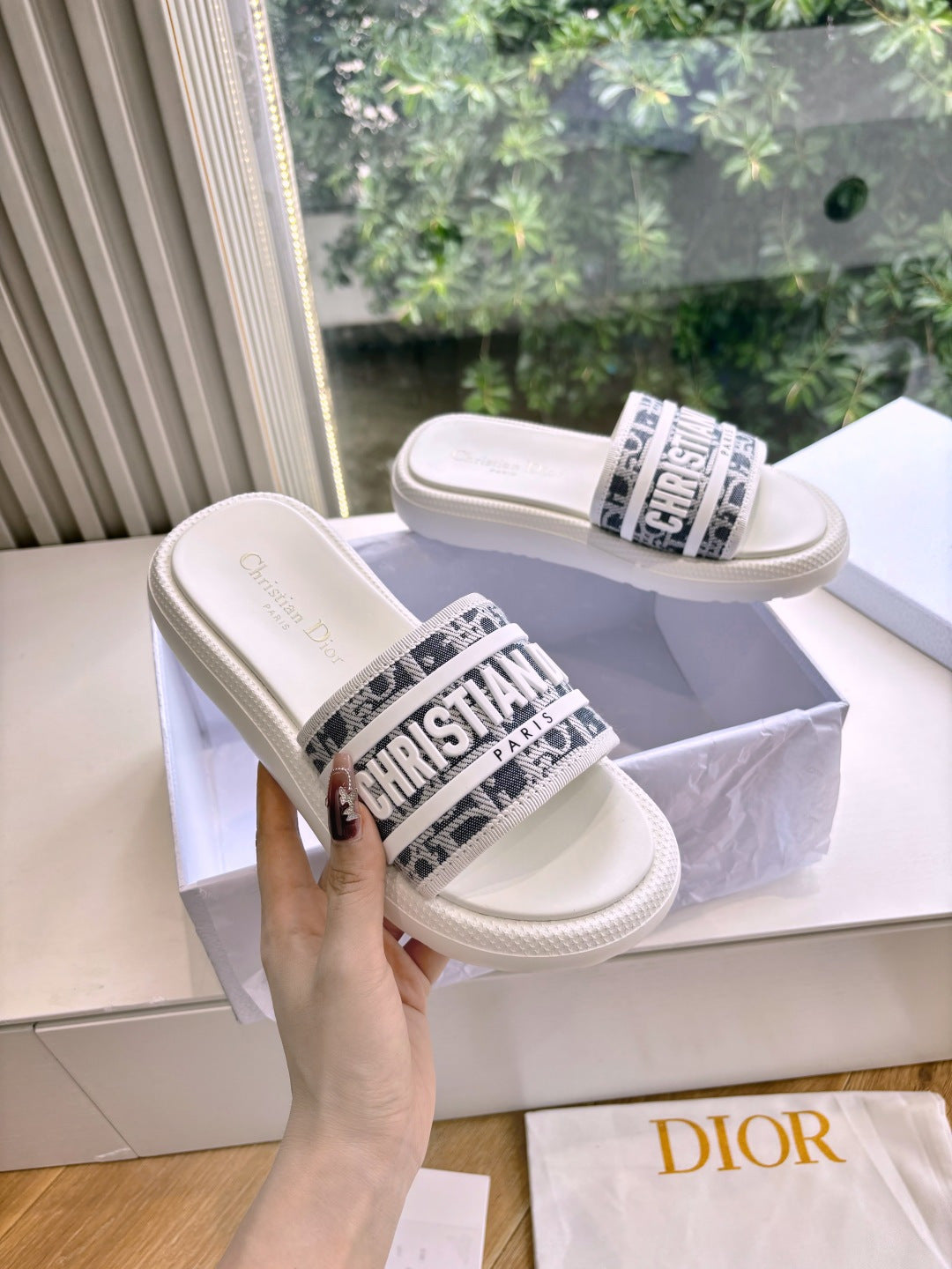 White Dior slide sandals on raised platform, logo band across front strap