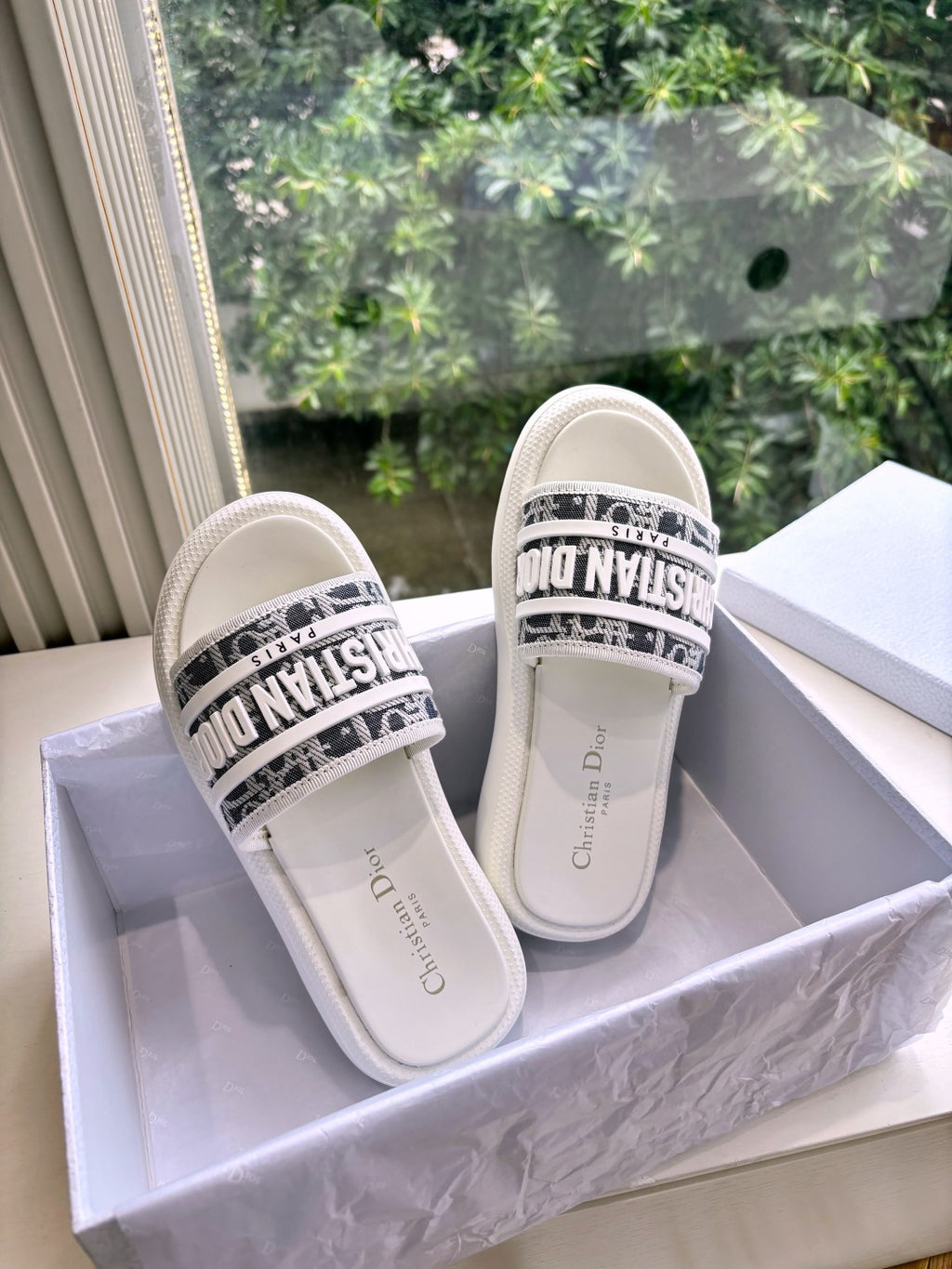 White Dior slide sandals, front view, black logo band across the strap