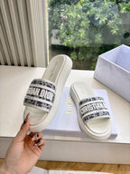 White Dior slide sandals, side angle, black logo band with woven texture