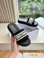 Black slide sandals with white "CHRISTIAN DIOR" logo strap, shown from front