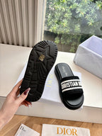 Black slide sandals showing textured outsole and logo strap