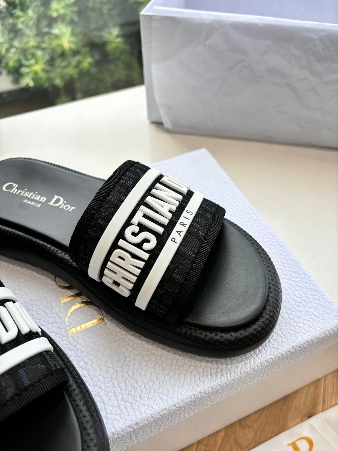 Black slide sandal with close-up of "CHRISTIAN DIOR" logo strap