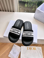 Pair of black slide sandals with white "CHRISTIAN DIOR" strap across the top