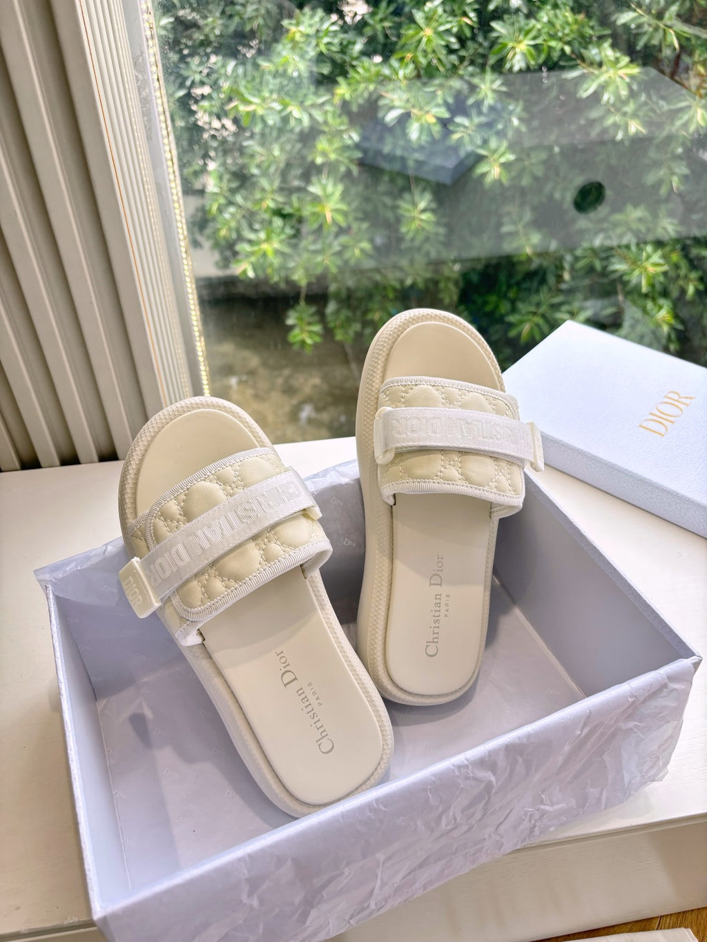 Dior ladies slide sandals, light beige, side view; cushioned strap with embossed lettering