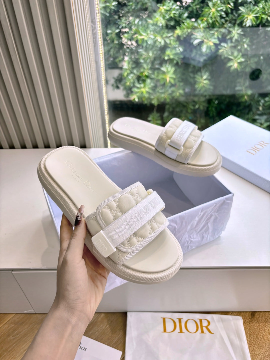 Dior ladies slide sandals, light beige, held in hand; wide strap with logo detailing