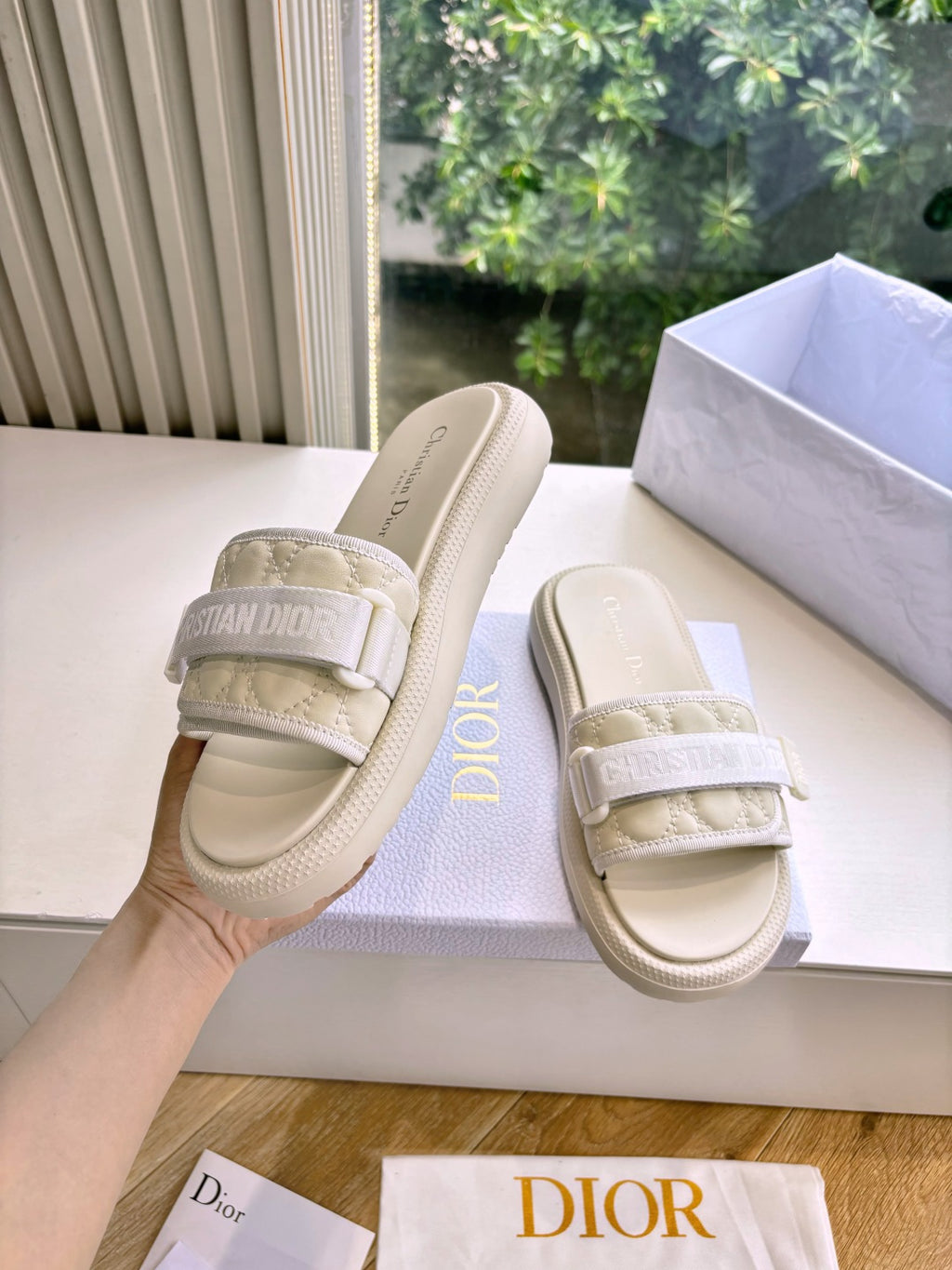 Dior ladies slide sandals, light beige, angled view; embossed strap over cushioned footbed