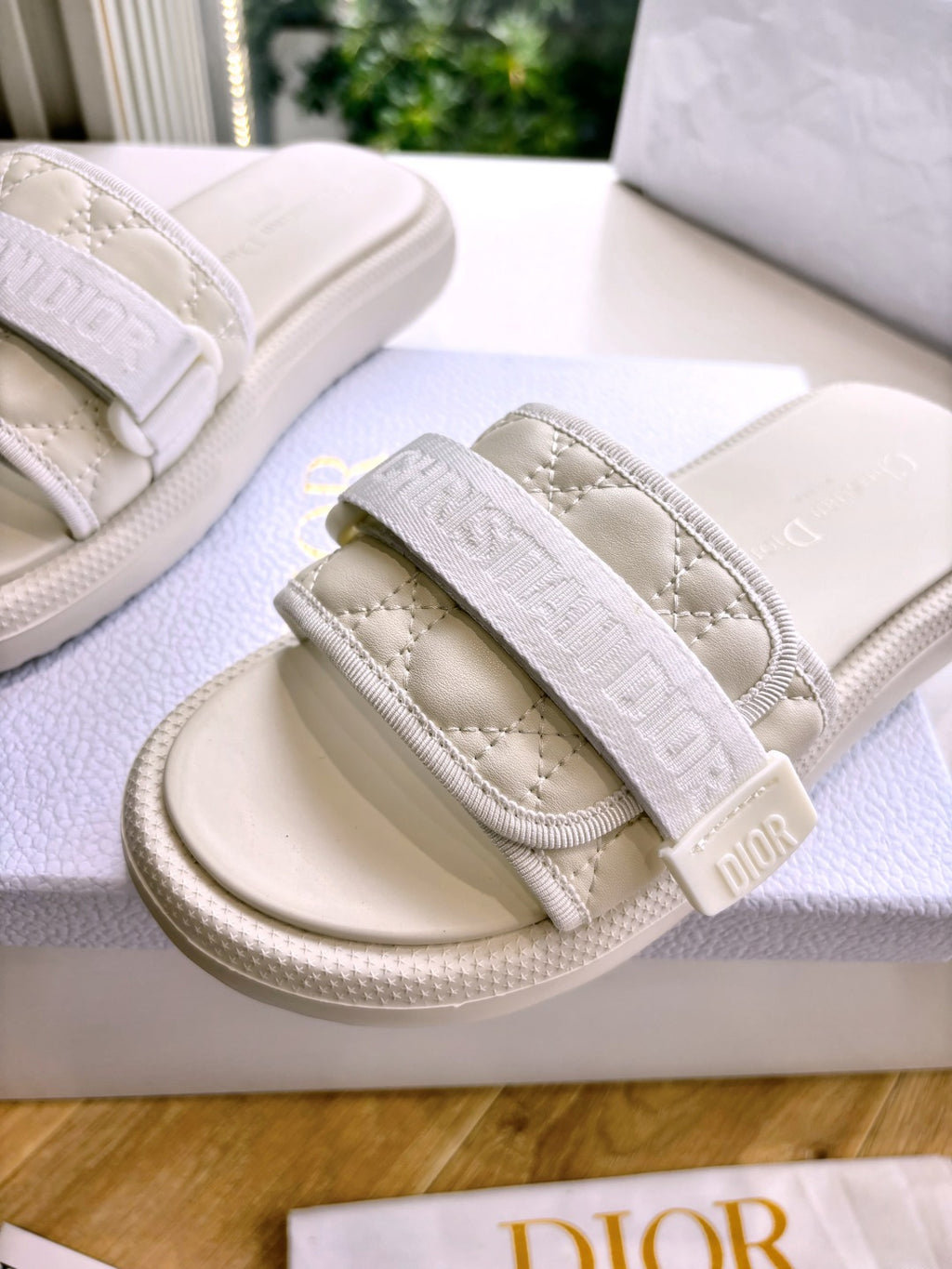 Dior ladies slide sandals close-up; embossed strap with Dior lettering on cushioned band
