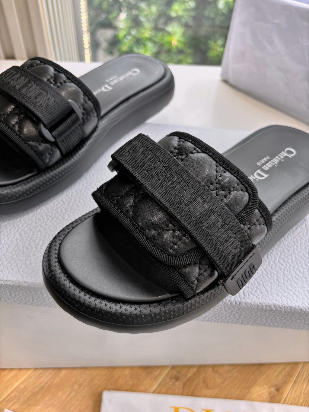 Black slide sandals close-up: wide textured strap with buckle and thick rubber sole