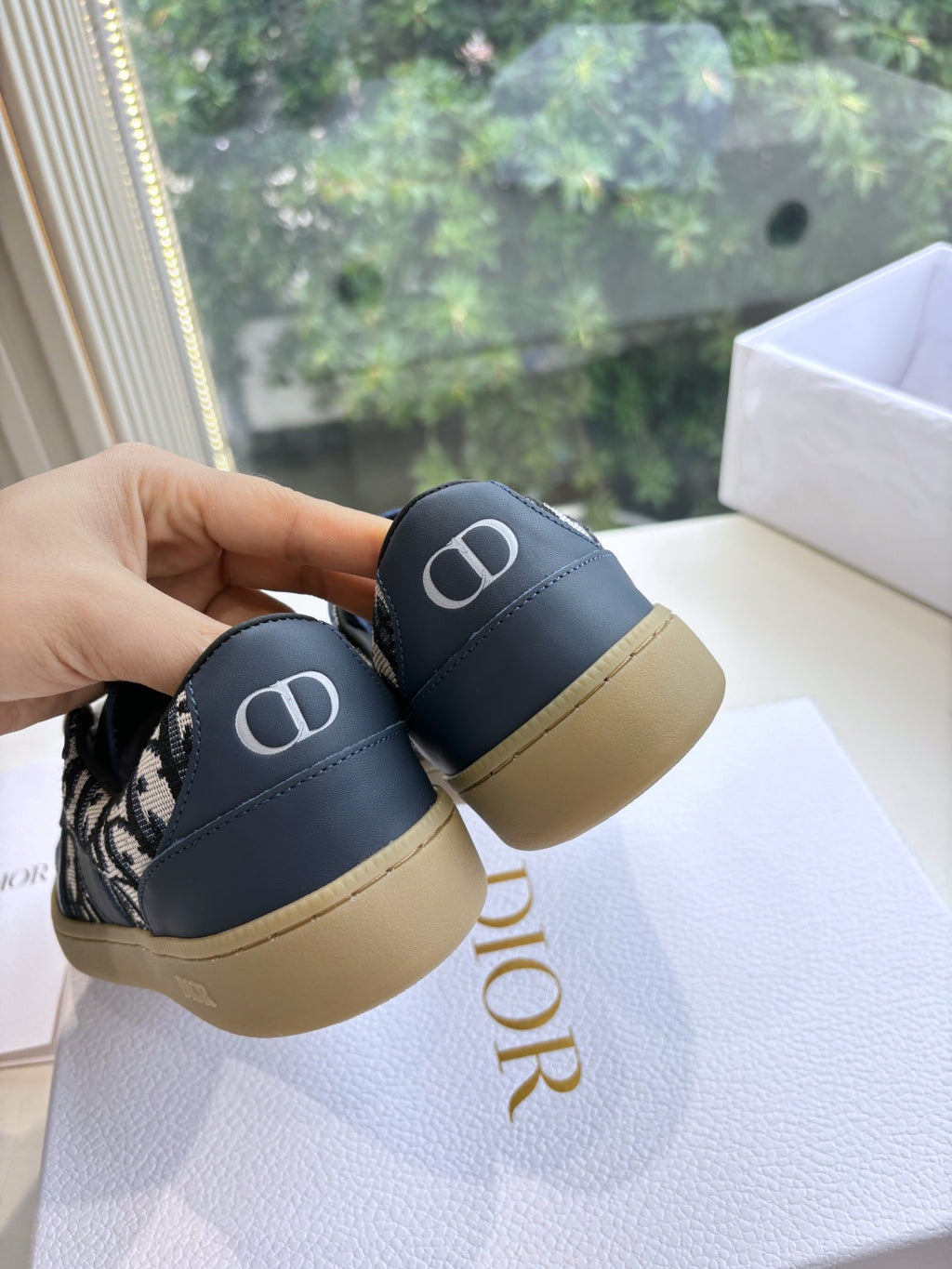 Heel close-up of navy low-top sneakers with CD logo and tan sole