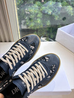 Close-up of navy low-top lace-up sneakers with logo print and off-white laces