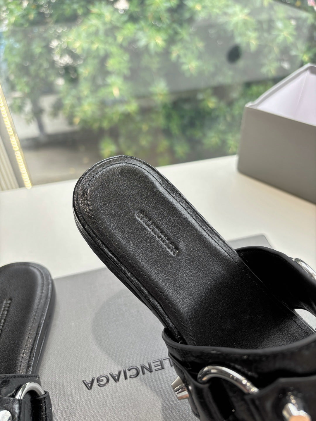 Black slide sandal close-up of textured footbed and strap buckle hardware
