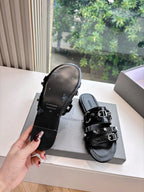 Black slide sandals with textured footbed and double buckle straps, angled view