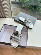 Pair of metallic silver slide sandals with silver buckles on wide straps