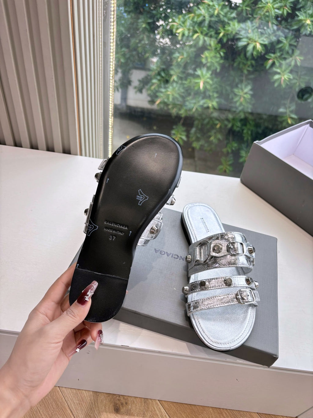 Metallic silver slide sandals showing black sole and silver buckle straps