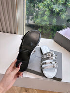 Metallic silver slide sandals showing black sole and silver buckle straps