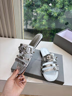 Silver metallic slide sandals with buckled straps and textured footbed