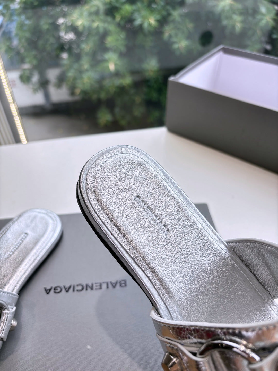 Balenciaga silver sandal footbed with engraved logo, side view of slide strap