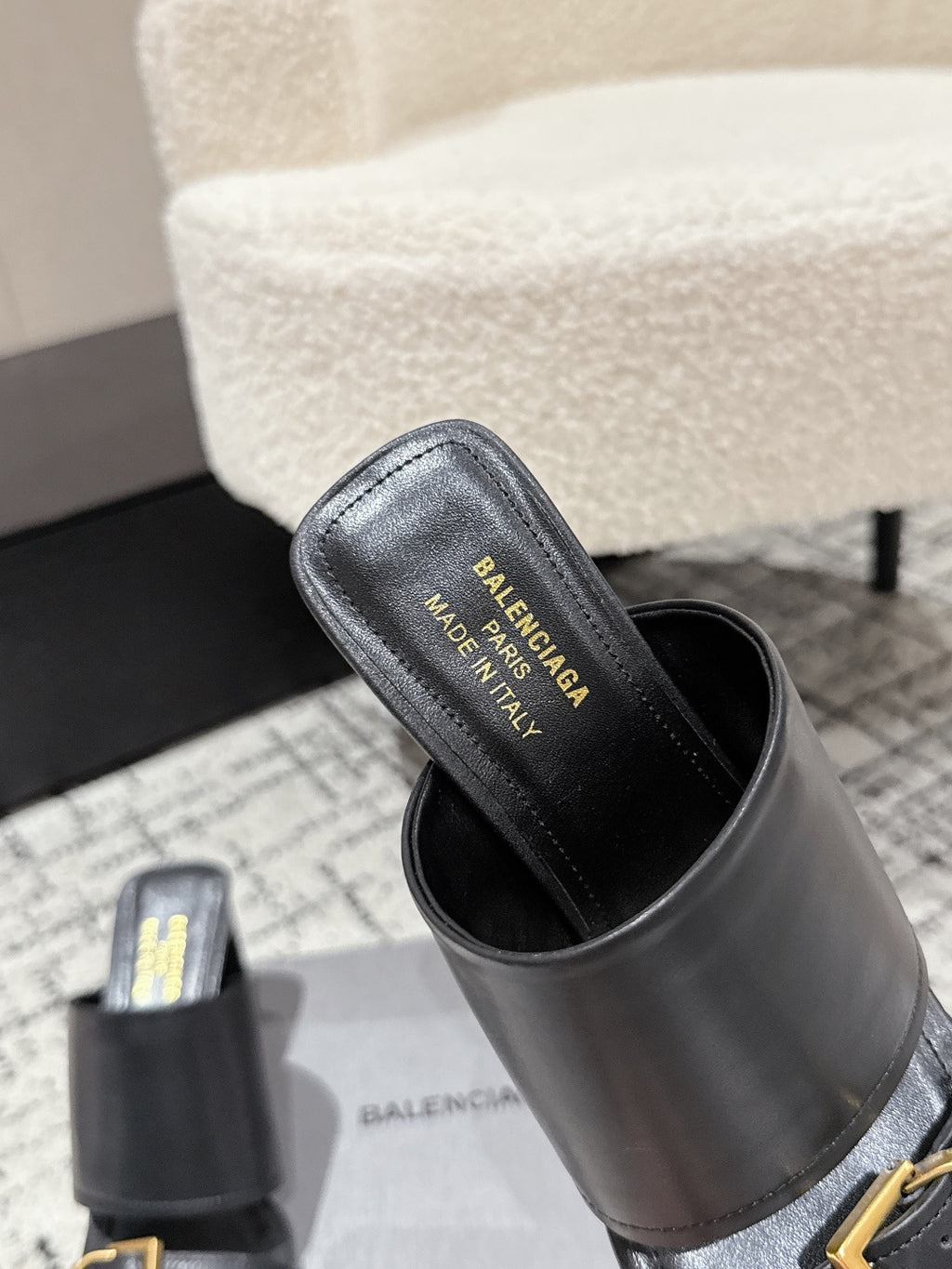Black slide sandal with wide strap and gold buckle, brand text on insole