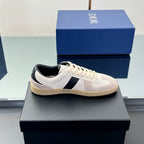 Low-top sneakers with white leather upper, navy stripe, and cream textured sole