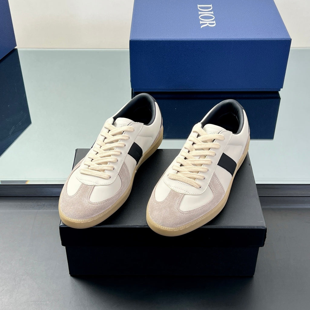 Two low-top sneakers with white uppers, navy stripe, and beige rubber sole