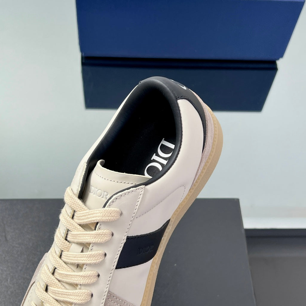 Toe and tongue view of white low-top sneakers with cream sole and navy panel