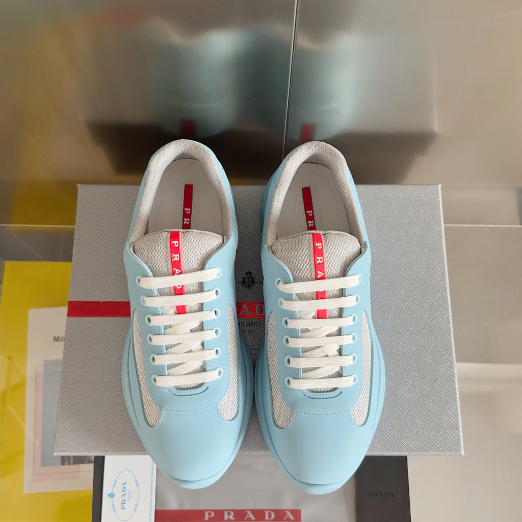 Prada unisex sneakers front view, light blue with beige panels and white lace-up closure