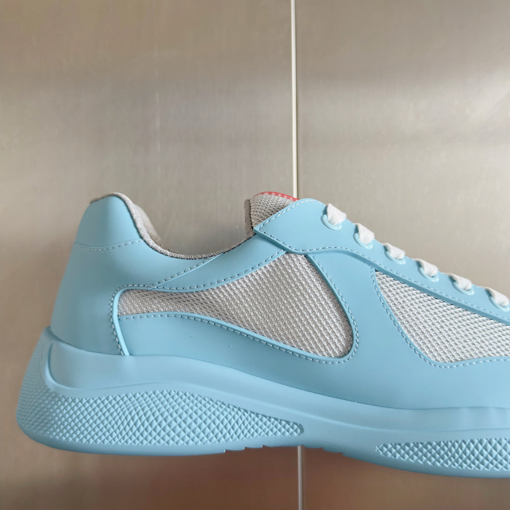 Prada unisex low-top sneaker side close-up, light blue leather with beige mesh overlay