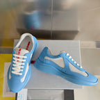 Prada unisex sneakers laid on box, light blue uppers with white lace and mesh details