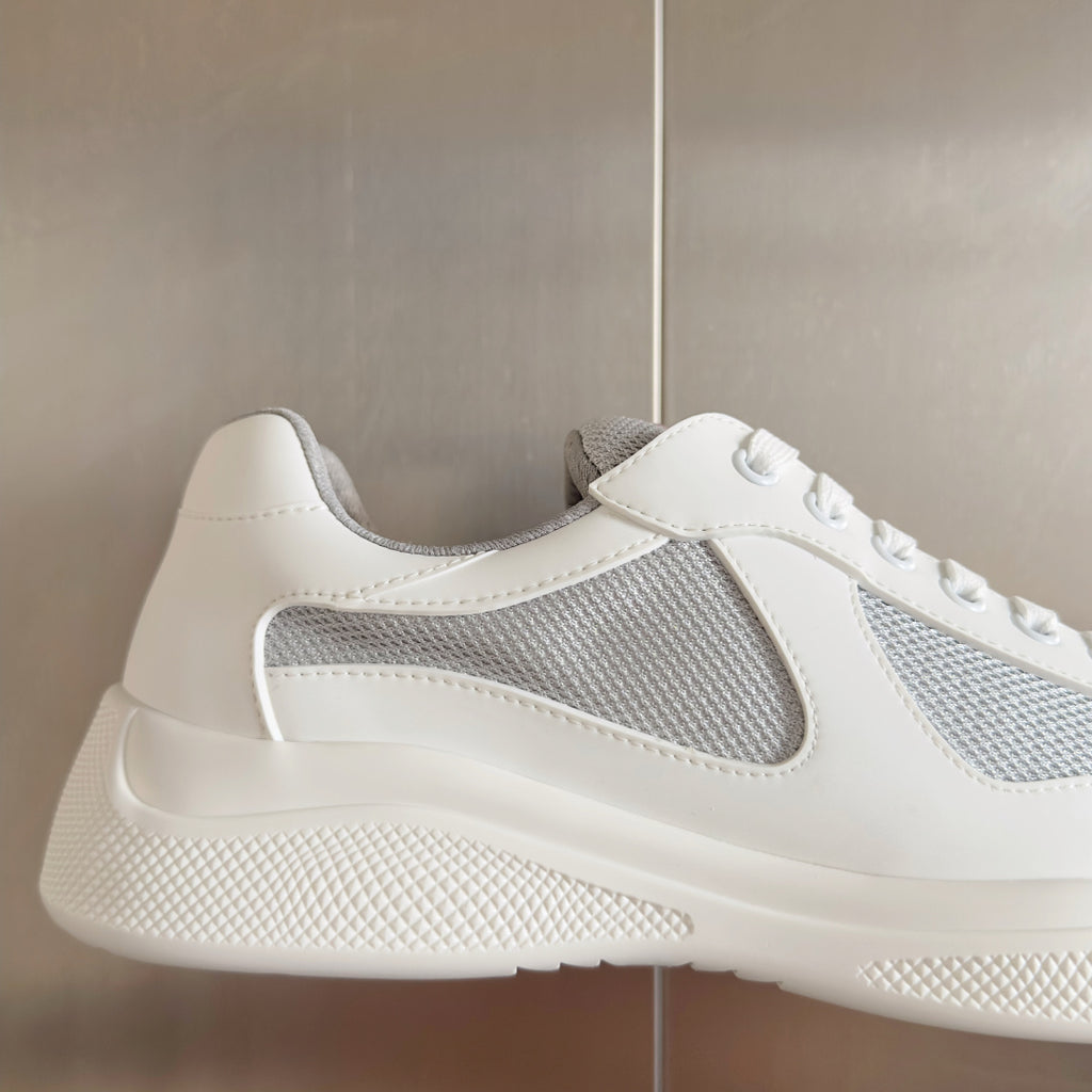 White Prada unisex sneaker with gray mesh side and red-striped heel label