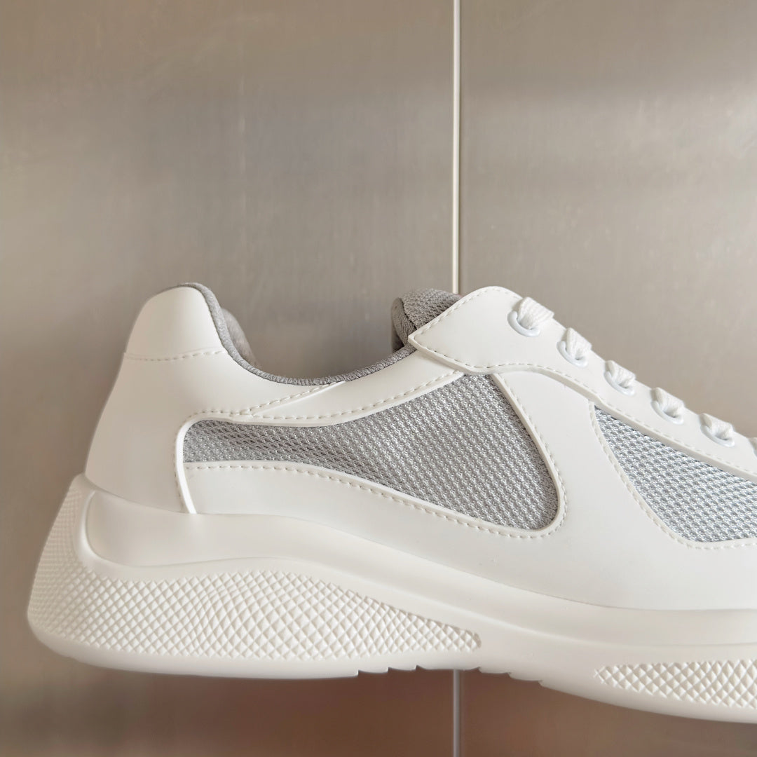 White Prada unisex sneaker with gray mesh side and red-striped heel label