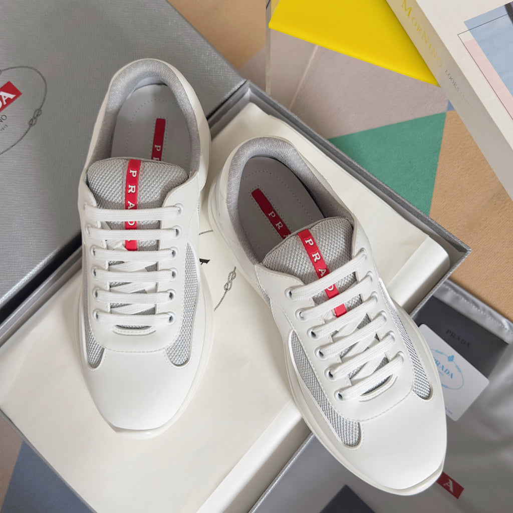 White Prada unisex lace-up sneakers with gray mesh panels and red logo tongue