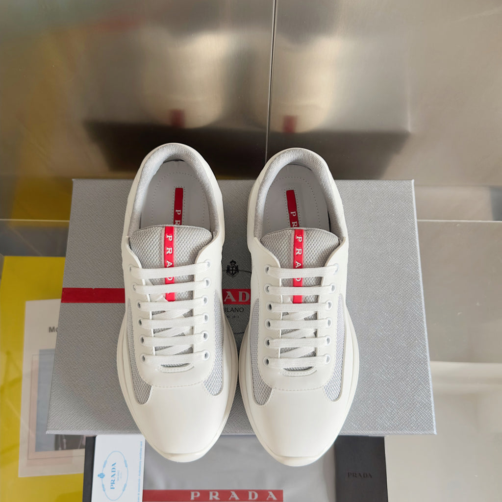 Pair of white Prada unisex lace-up sneakers with red logo on tongue