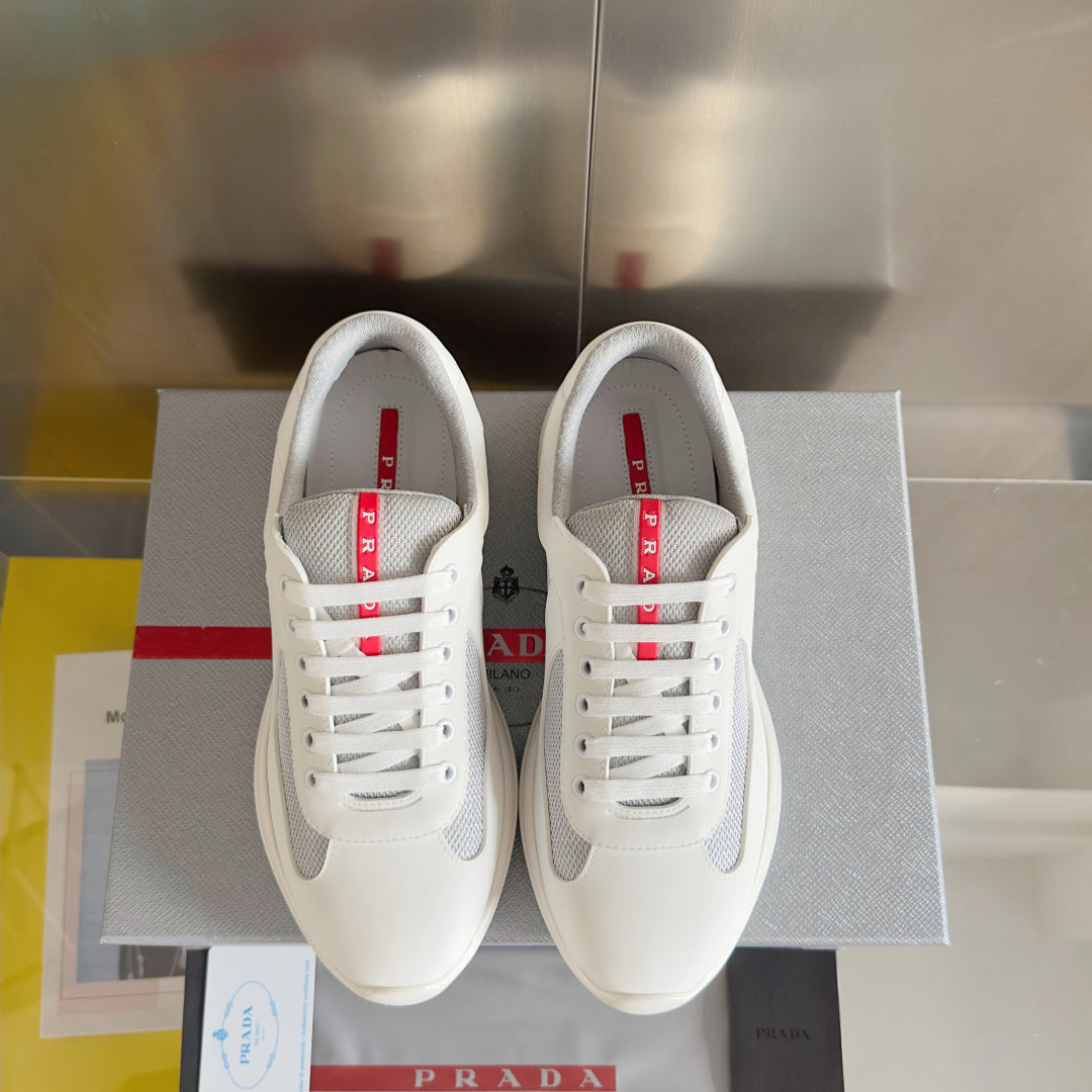 Pair of white Prada unisex lace-up sneakers with red logo on tongue