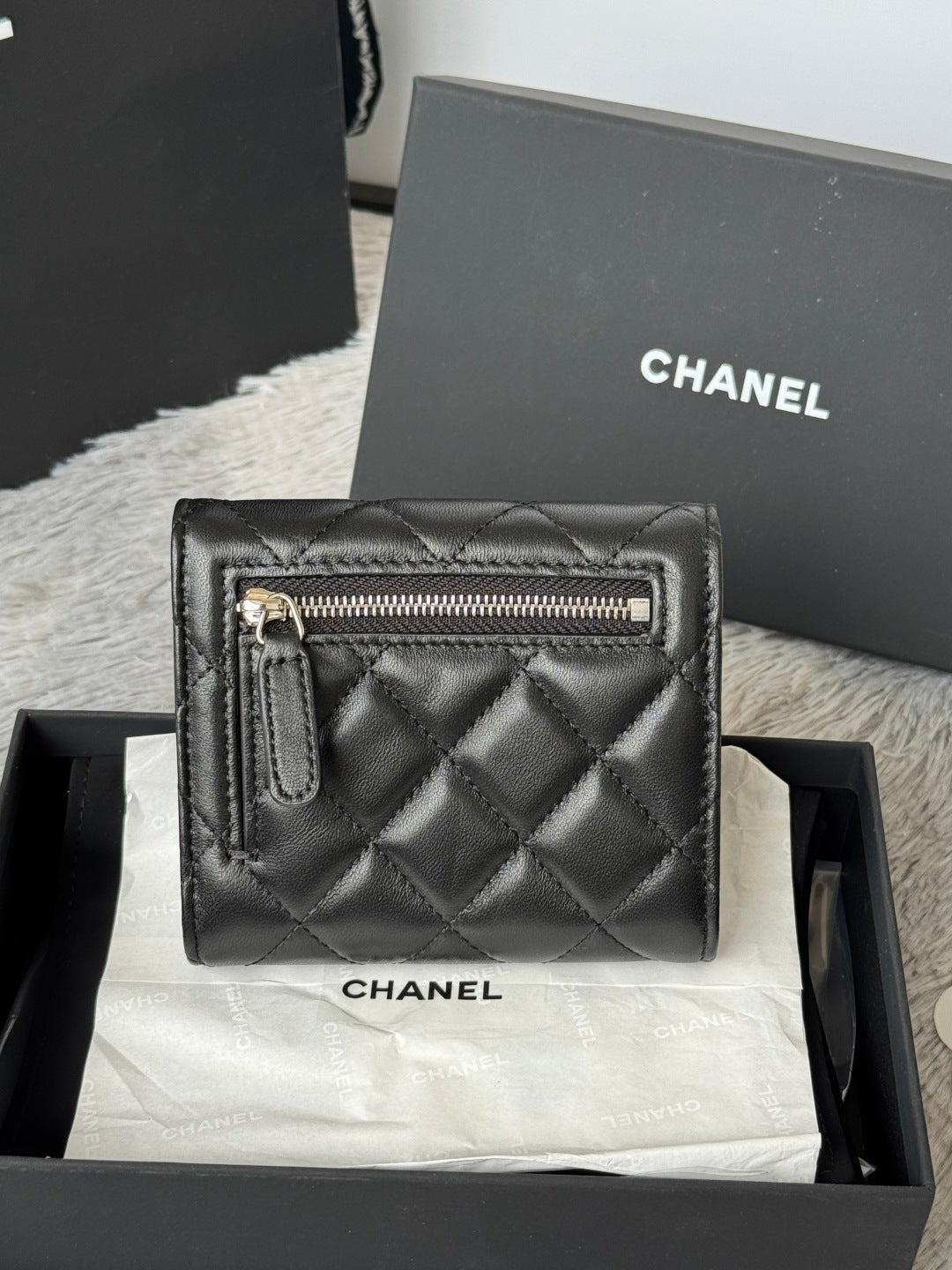 Small quilted leather flap bag, black, side with zippered pocket and CHANEL logo.