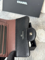 Small leather wallet-style bag, brown and black, open with CHANEL text and clasp.