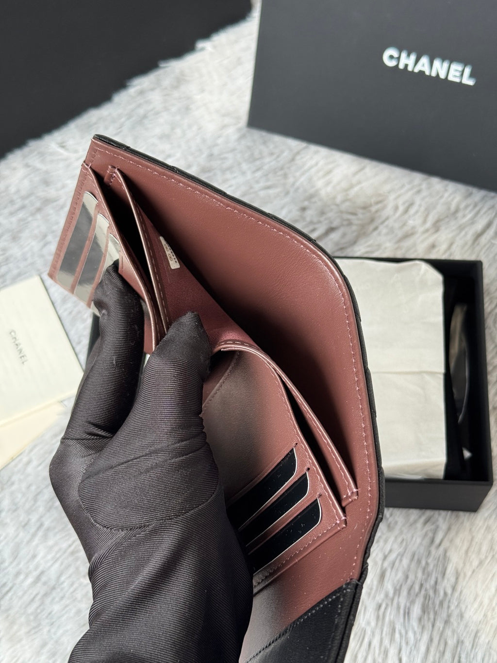 Small leather wallet-style bag, brown, open view with card slots and CHANEL interior.