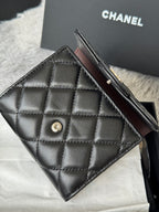 Black quilted small bag with flap, front snap button, and slim strap