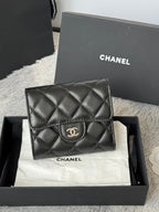 Small quilted leather flap bag, black, front view with CHANEL CC logo on clasp.