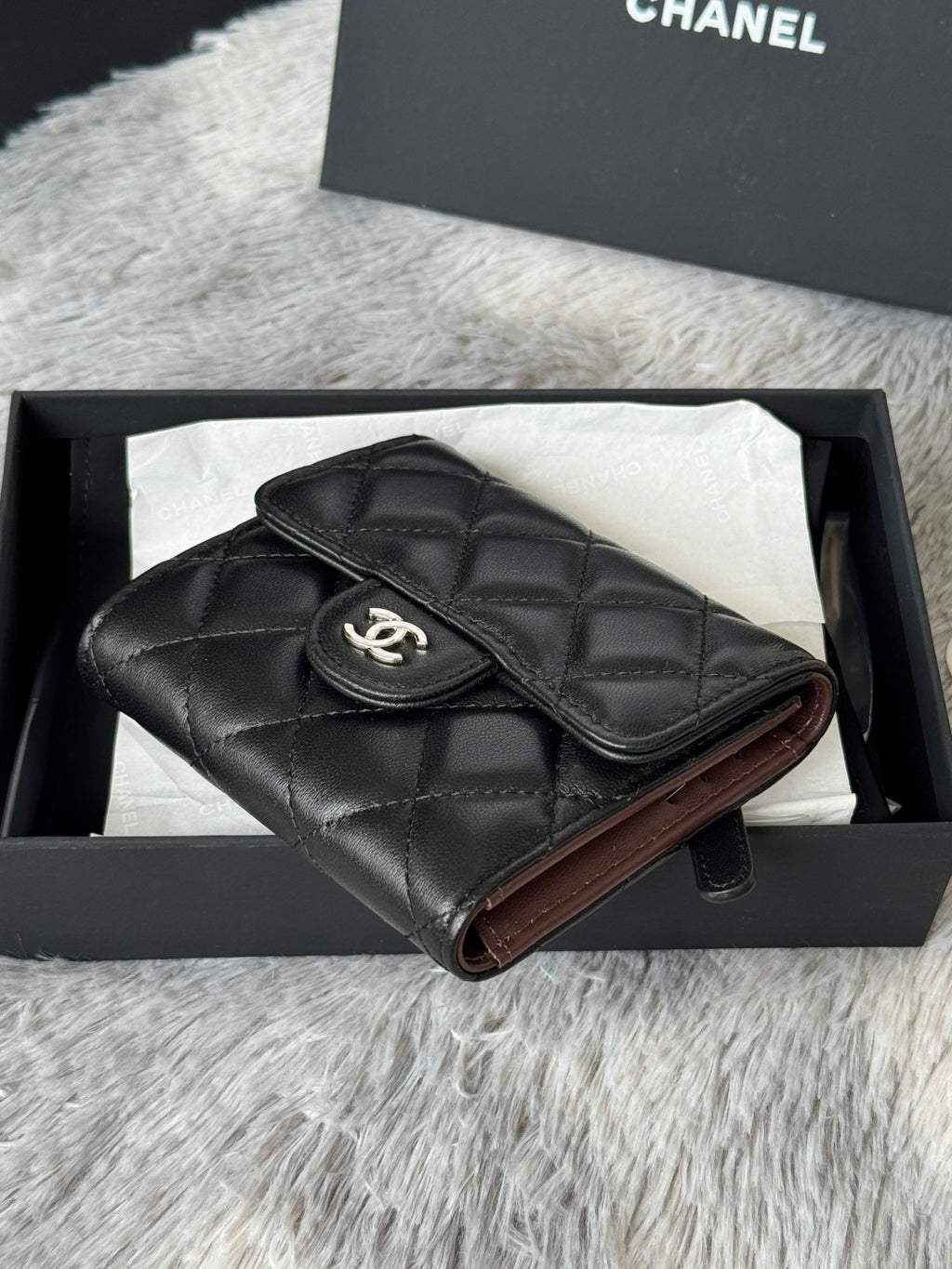 Small quilted leather flap bag, black, angled view with CHANEL CC emblem on flap.