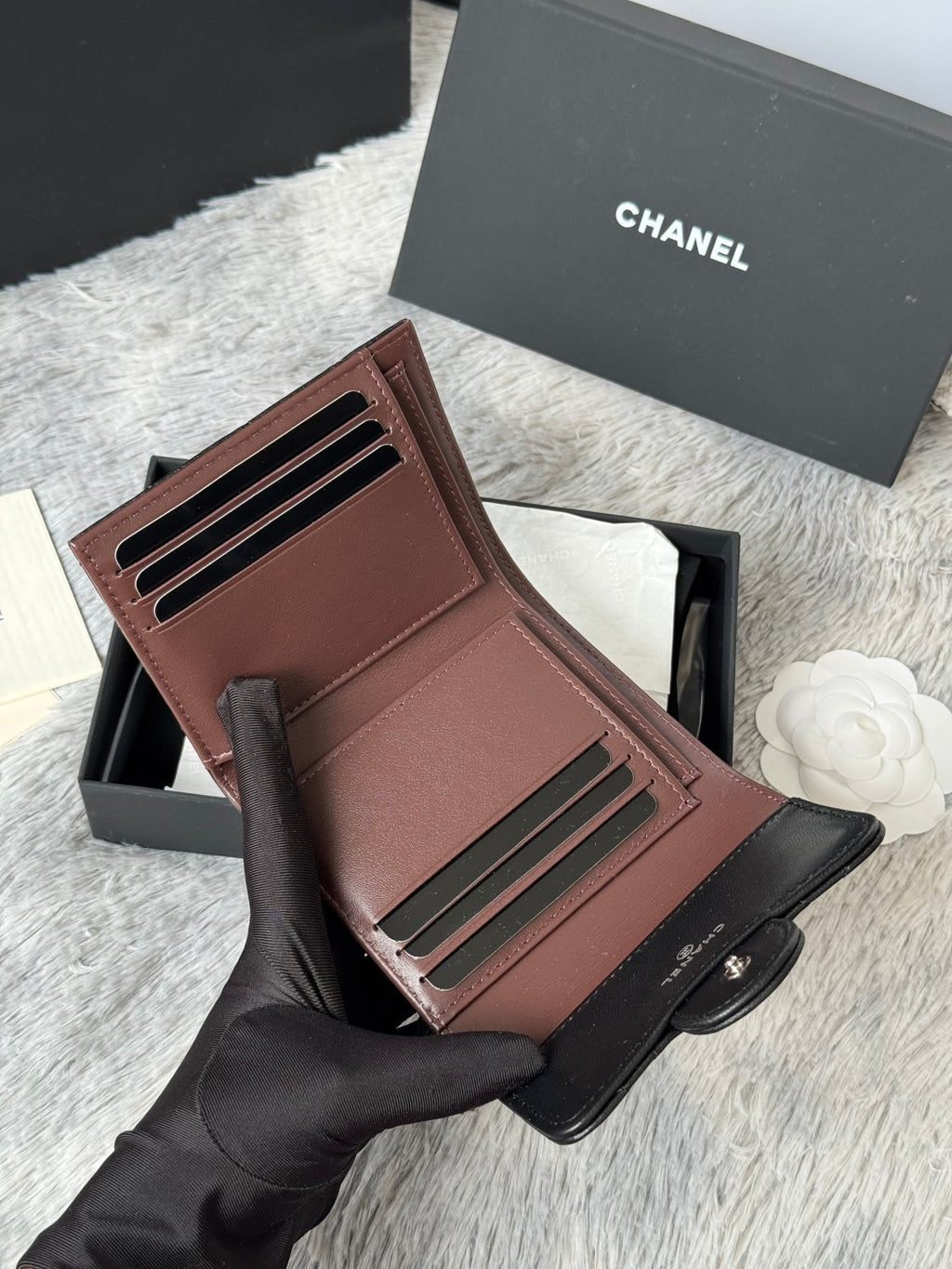Small leather wallet-style bag, brown, open with card slots and CHANEL interior detail.