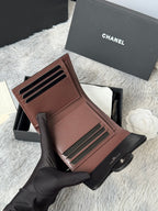 Small leather wallet-style bag, brown, open with card slots and CHANEL interior detail.